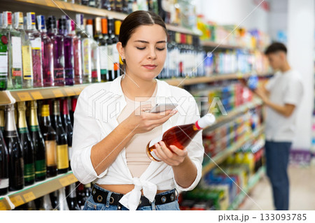 Young woman scanning barcode on wine bottle with smartphone Young woman scanning barcode on wine bottle with smartphone 133093785