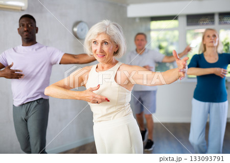 Elderly woman is engaged in dance lesson and repeats basic movements for pair ballroom dancing Elderly woman is engaged in dance lesson and repeats basic movements for pair ballroom dancing 133093791