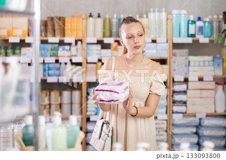 Young woman chooses feminine pads at pharmacy 133093800