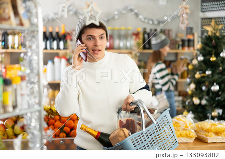 Guy talking on her mobile phone - asking for advice on what products to buy at supermarket for Christmas 133093802