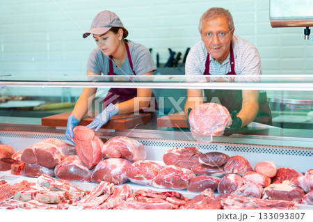 Male farmer of meat products in butcher shop offers to buy fresh beef tenderloin. 133093807