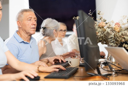 Concentrated elderly man immersed in using computer in library Concentrated elderly man immersed in using computer in library 133093968