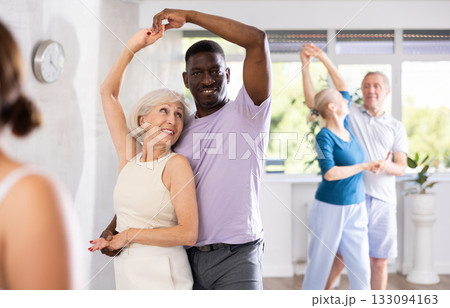 Mature men and women practicing Ballroom dances in training room 133094163