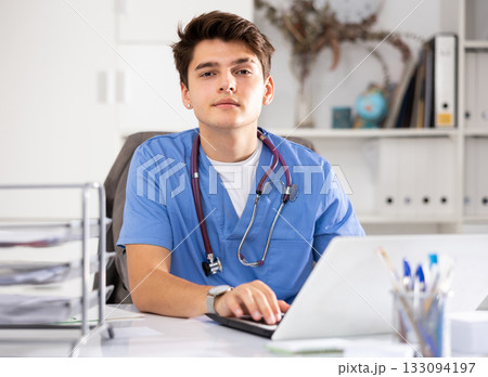 Focused doctor therapist works at a hospital computer, studying outpatient cards patients in resident office 133094197