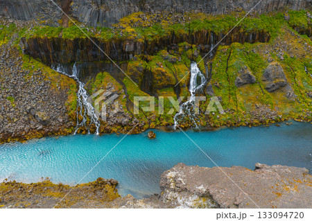 Turquoise water flows through Sigoldugljufur Canyon, Iceland, with moss covered cliffs and cascading waterfalls over basalt rock formations. Turquoise water flows through Sigoldugljufur Canyon, Iceland, with moss covered cliffs and cascading waterfalls over basalt rock formations. 133094720