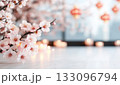 Delicate cherry blossom branches illuminate a serene indoor setting with soft lighting. 133096794