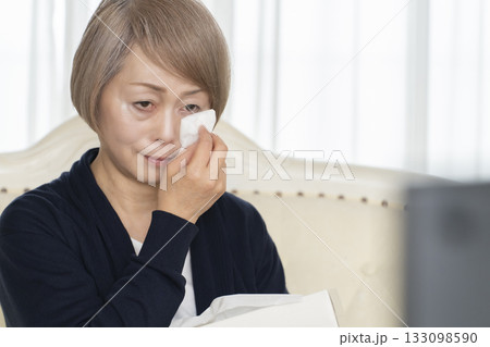 リビングで悲しいテレビを観て泣くシニア女性 リビングで悲しいテレビを観て泣くシニア女性 133098590