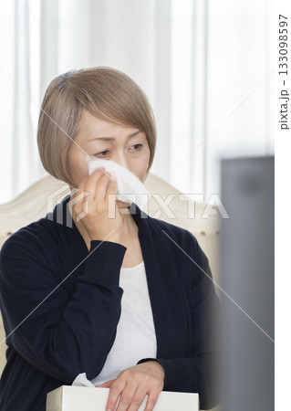 リビングで悲しいテレビを観て泣くシニア女性 133098597