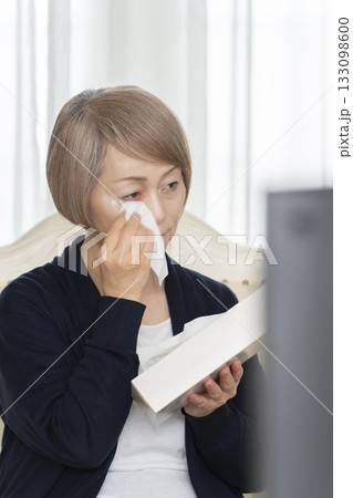 リビングで悲しいテレビを観て泣くシニア女性 リビングで悲しいテレビを観て泣くシニア女性 133098600