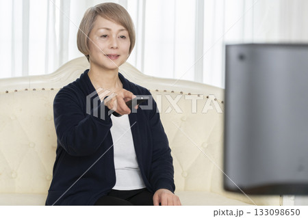 リビングでテレビのリモコンを持つシニア女性 リビングでテレビのリモコンを持つシニア女性 133098650