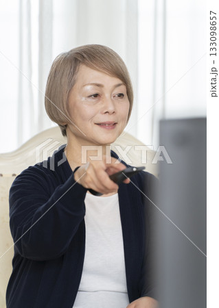 リビングでテレビのリモコンを持つシニア女性 リビングでテレビのリモコンを持つシニア女性 133098657