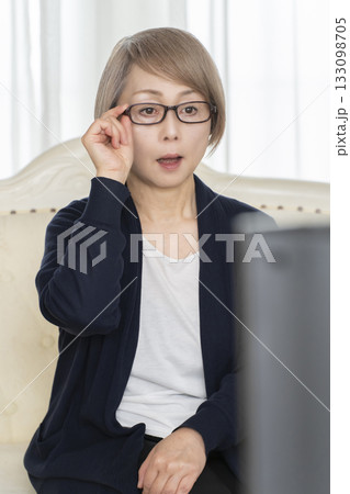 リビングでめがねをかけてテレビを観るシニア女性 リビングでめがねをかけてテレビを観るシニア女性 133098705