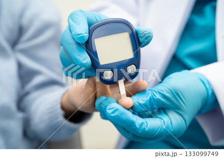 Asian doctor using digital glucose meter for check sample blood sugar level to treatment diabetes. 133099749
