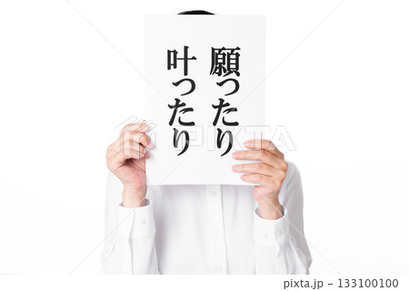 願ったり叶ったりと書かれた紙を両手で持つ白いシャツを着た人物 133100100