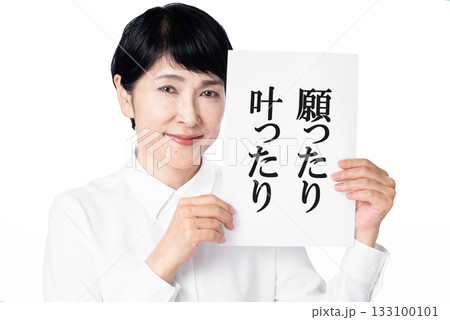 願ったり叶ったりと書かれた紙を両手で持ち微笑む白いシャツを着たシニア女性 133100101