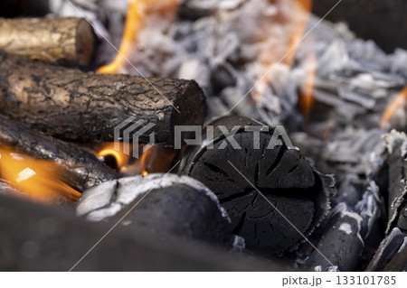 a bonfire made of logs from trees and an orange flame during the preparation of the barbecue for cooking meat, burning logs in the grill for hot coals and roasting meat a bonfire made of logs from trees and an orange flame during the preparation of the barbecue for cooking meat, burning logs in the grill for hot coals and roasting meat 133101785
