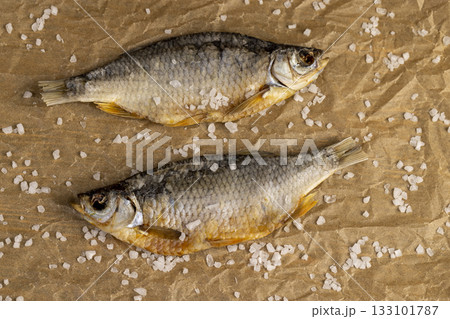 white salt and dried fish for long-term storage by dehydrating fish in the sun, dried fish in scales ready for human consumption, sprinkled with white salt crystals 133101787