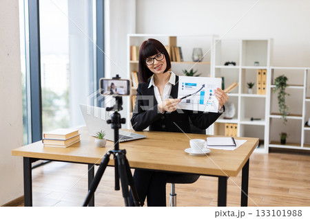 Caucasian woman presenting business data in office, recording blog or video with professional equipment Caucasian woman presenting business data in office, recording blog or video with professional equipment 133101988