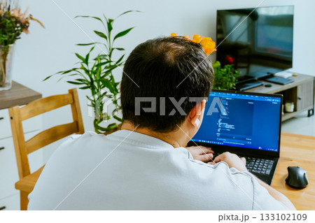 A man sits at a laptop and uses AI, seen from behind. 133102109