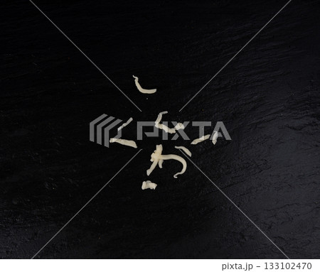 Grated mozzarella cheese on black background. Shredded mozarella texture 133102470