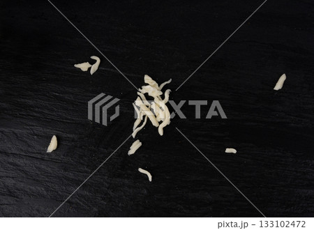 Grated mozzarella cheese on black background. Shredded mozarella texture 133102472