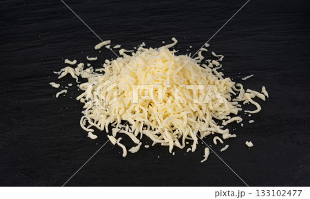 Grated mozzarella cheese on black background. Shredded mozarella texture 133102477