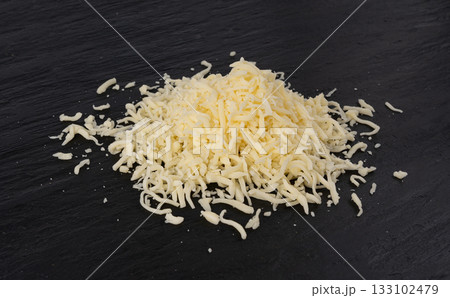 Grated mozzarella cheese on black background. Shredded mozarella texture 133102479