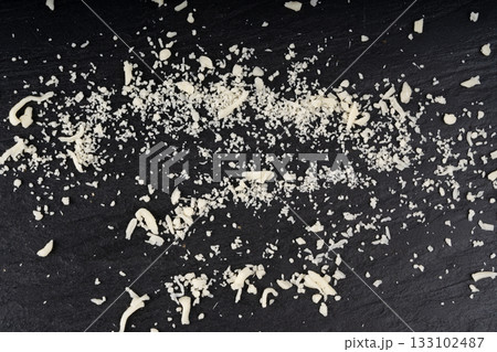 Grated mozzarella cheese on black background. Shredded mozarella texture 133102487