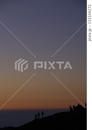 早朝の山頂で御来光の瞬間を待つカメラマンたちのシルエット(冬の朝，望遠ズーム撮影) 133104272