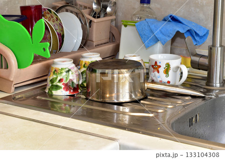 The washed dishes are drying on the sink. The washed dishes are drying on the sink. 133104308