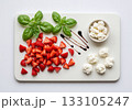 Fresh strawberries basil leaves ricotta cheese arranged artistically on white marble cutting board with balsamic drizzle 133105247