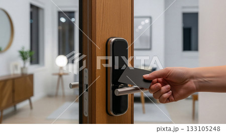 Smart keycard access system on wooden door in contemporary home interior with hand holding electronic entry card 133105248