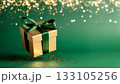 Luxurious golden gift box adorned with emerald satin ribbon against magical bokeh sparkle background 133105256