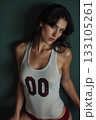Athletic brunette model wearing vintage numbered tank top with dramatic studio lighting and face tattoos 133105261