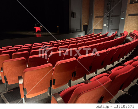 Red chairs and stage view in theater hall. Stillness, architecture, and cultural anticipation before creative expression begins. 133105573