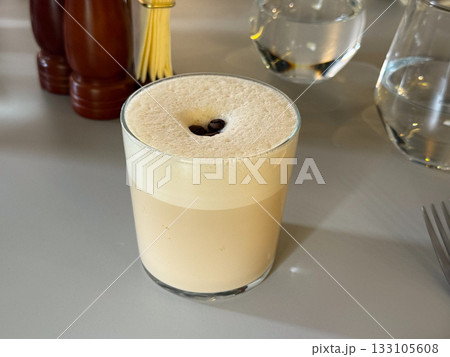 Iced coffee with foam and coffee beans. Energy, comfort, and modern lifestyle moment centered around caffeine ritual and taste. Copy space 133105608