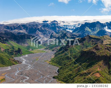 Aerial view of Mulagljufur Canyon in Iceland, featuring lush green cliffs, a braided river, volcanic soil, a glacier, and rugged mountains. Aerial view of Mulagljufur Canyon in Iceland, featuring lush green cliffs, a braided river, volcanic soil, a glacier, and rugged mountains. 133108192