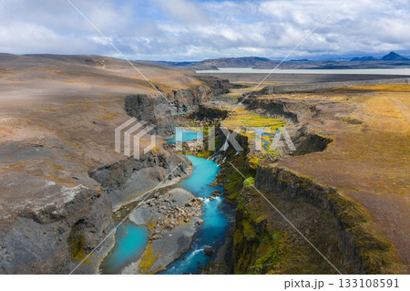 Sigoldugljufur Canyon, Iceland, features turquoise streams, cascading waterfalls, green moss, and rocky terrain under a partly cloudy sky. Sigoldugljufur Canyon, Iceland, features turquoise streams, cascading waterfalls, green moss, and rocky terrain under a partly cloudy sky. 133108591