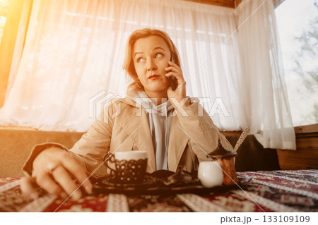 Woman Talking on Phone at a Cafe Woman Talking on Phone at a Cafe 133109109