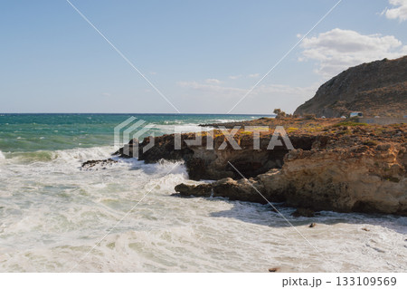 Furious storm and white foam turquoise waves crashing on rocky coast. 133109569