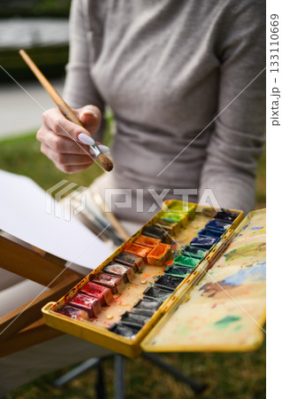 Close-up of artist mixing colors on watercolor palette. Close-up of artist mixing colors on watercolor palette. 133110669