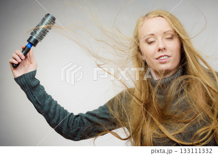 Girl styling her long hair 133111332