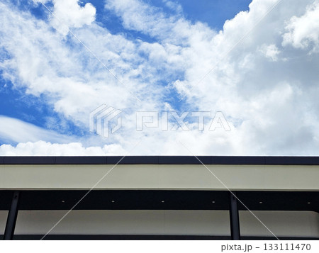 Blue sky with white clouds over the modern building roofline. Blue sky with white clouds over the modern building roofline. 133111470
