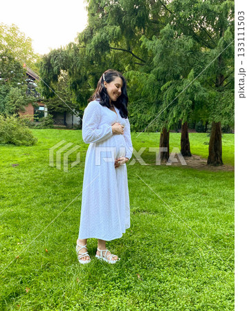 Pregnant Woman Holding Flowers in Park 133111503