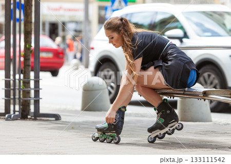 Young woman putting roller skates on 133111542