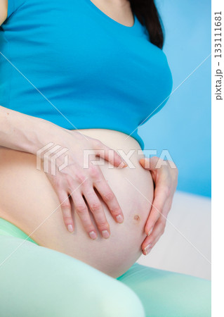 Pregnant woman caressing her belly Pregnant woman caressing her belly 133111681