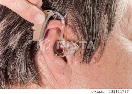 Closeup senior woman using hearing aid 133111757