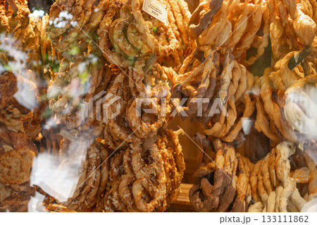 Close-up view of a chocolate-covered pretzel sprinkled with almond pieces, placed inside a shop display. The glossy chocolate coating and crunchy nut texture create an appetizing and inviting visual Close-up view of a chocolate-covered pretzel sprinkled with almond pieces, placed inside a shop display. The glossy chocolate coating and crunchy nut texture create an appetizing and inviting visual 133111862