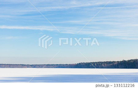 A serene winter landscape features a vast snow covered frozen lake A serene winter landscape features a vast snow covered frozen lake 133112216