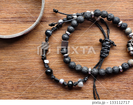 Close-up of handmade black bead bracelets with metal accents on a wooden surface. Minimal and natural jewelry style for product display, craft design, and fashion accessories concepts. 133112717